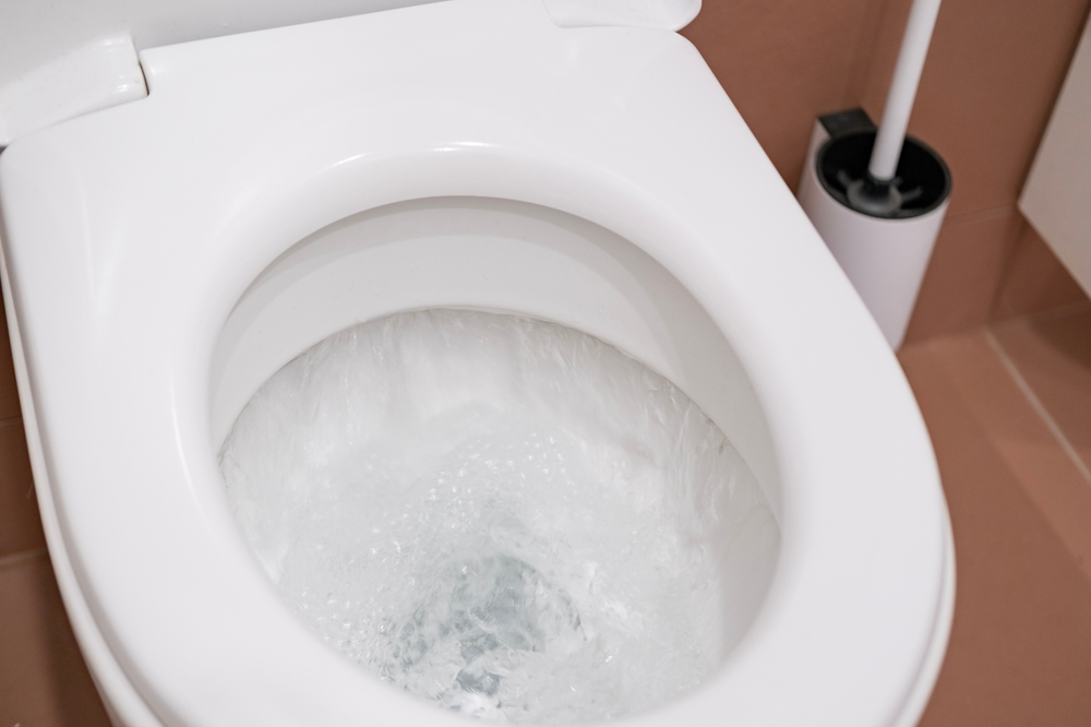 A closeup of a toilet bowl while the water is swirling down the drain after flushing
