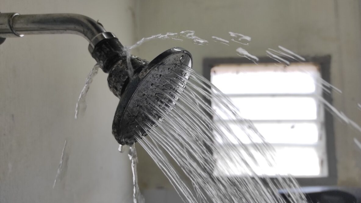 a broken shower head with water spraying in all directions